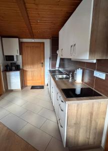 a kitchen with white cabinets and a wooden ceiling at Ferienhaus Niederbichler in Gnesau