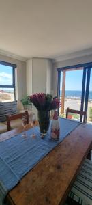 a table with two glasses and a vase with flowers on it at MaKarLi Blu in St. Helena Bay +37 photos