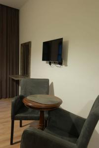a living room with two chairs and a table and a tv at Hotel Nicolo in Tbilisi City