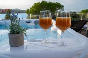 two glasses of wine sitting on a table next to a pool at Beachfront house Miamore - 10 m from the sea in Pašman