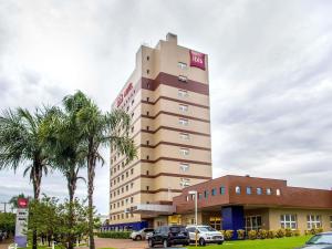 a tall building with cars parked in front of it at ibis Araçatuba in Araçatuba