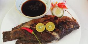 a plate with a piece of fish and a cup of coffee at Bamboo Payag Batangas in Laurel