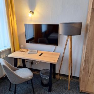 a desk with a lamp and a chair in a room at Pension Kursprung in Bad Brambach