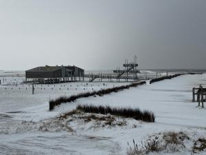 a beach with a pier and a building in the snow at Villa Meeresglück in Dornum