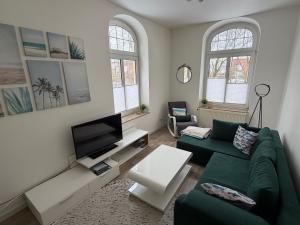 a living room with a green couch and a tv at Villa Meeresglück in Dornum