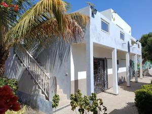 a white house with stairs and a palm tree at Guorgui's bed in Ndangane