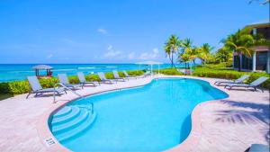 a swimming pool with chairs and the ocean in the background at Northern Lights #6 Condo in Old Man Bay