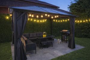 a gazebo with a couch and a table and lights at Pokoje Koral in Mikołajki