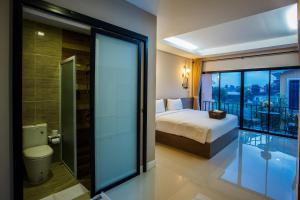 a bedroom with a bed and a bathroom with a balcony at Sata House Boutique Resort in Nakhon Ratchasima
