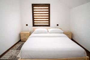 a bedroom with a white bed and a window at Casa de vacanta Naty in Colibiţa