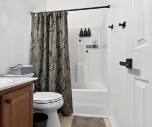 a bathroom with a shower curtain and a toilet at The Executive Suite in McDonough