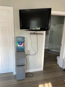 a flat screen tv on a wall with a water container at Oakhill Oasis guest house in Moores Mills