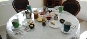 a white table with plates and utensils on it at Hospedaje Campestre Ranco Naturaleza - Desayuno incluido in Lago Ranco