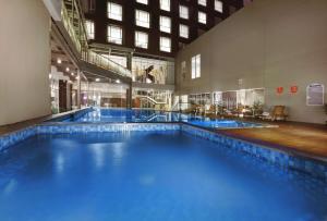 a large swimming pool with blue water in a building at ASTON Pasteur in Bandung
