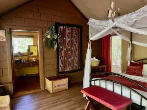 a bedroom with a canopy bed and a bathroom at Ikweta Safari Camp in Kinna