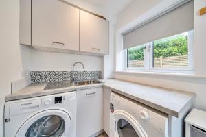 a white laundry room with a washer and dryer at Winterbourne House in Fleet