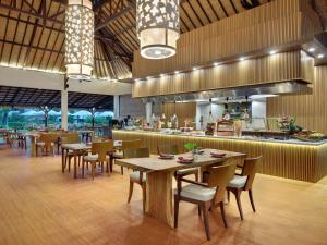 a restaurant with tables and chairs and a kitchen at Novotel Bali Nusa Dua in Nusa Dua