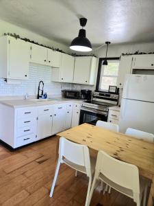 a kitchen with a wooden table and white cabinets at Cozy Cabin 2 beds Mtn view in Franklin