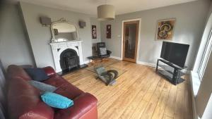 a living room with a leather couch and a fireplace at BALLYHOURA, Kildorrery, Beautiful 5 bed quite convenient location in Kildorrery