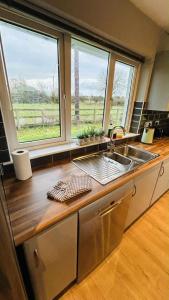 a kitchen with a sink and two windows at BALLYHOURA, Kildorrery, Beautiful 5 bed quite convenient location in Kildorrery