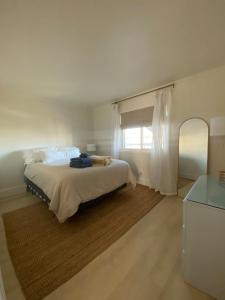 a white bedroom with a bed and a window at Pearl on the Point in Carolina Beach