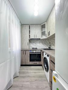a kitchen with white cabinets and a washer and dryer at Riverside Apartment in Lugoj