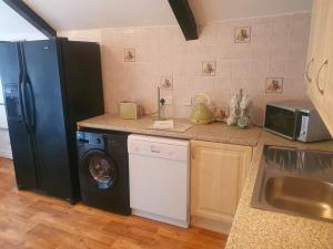 a kitchen with a refrigerator and a washing machine at Rosecraddoc Manor - Coachman's in Saint Cleer