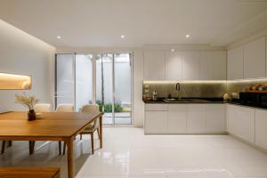 a kitchen with white cabinets and a wooden table at Bhumidol Home near Don Muang Airport in Lak Si