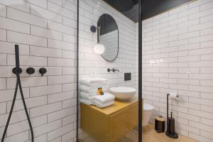 a white tiled bathroom with a sink and a mirror at Selah Residence in Oradea +30 photos