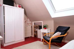 a attic room with a chair and a white cabinet at Les Roses in Santec