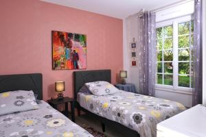 two beds in a room with pink walls and windows at Les Roses in Santec