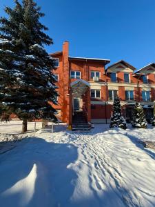 a building in the snow with a christmas tree in front at Perlos Apartamentai 12 in Birštonas