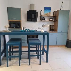 a blue kitchen with a blue table and stools at Le Pavillon du trou d'eau in La Saline les Bains