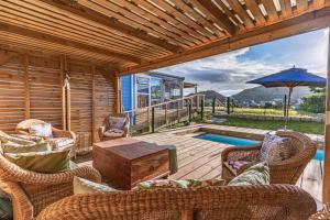 a patio with wicker chairs and a table and a pool at The Mermaid's Tail in Pringle Bay