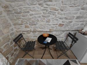 a table and chairs in front of a stone wall at Le Stanze sul Colle in Palo del Colle