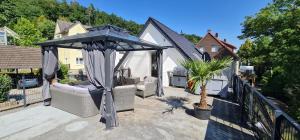 a patio with a gazebo and chairs on a balcony at Pension am Bach Prinz Charming in Fuldatal