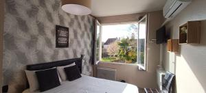 a bedroom with a large bed and a window at Hôtel Le P'tit Monde in Montignac