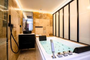 a bathroom with a tub and a shower and a sink at Cristalys Loveroom & Spa in Montpellier