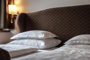 a bed with a headboard and two pillows at Hotel Geisler Tulfes in Tulfes