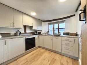 a kitchen with white cabinets and a large window at Number 22, Castle Street in Hay-on-Wye
