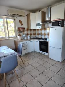 a kitchen with a white refrigerator and a table at Apartmani Barba Sevid in Sevid