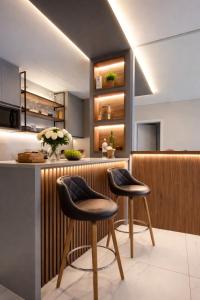 a kitchen with two stools at a counter at Summerview novo , 2 piscinas e 2 jacuzzis, 2 quartos Novo! in Itapema +17 photos