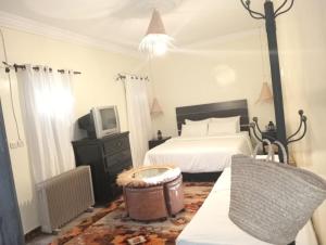 a bedroom with a bed and a tv and a couch at Dar Tissila in Marrakesh