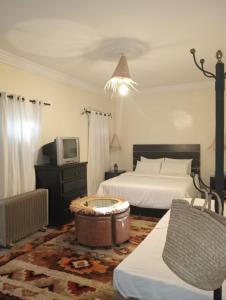 a bedroom with two beds and a tv and a tub at Dar Tissila in Marrakesh