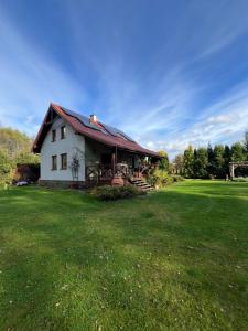 a white house with a red roof on a grass field at Dom w Sąpach in Sąpy