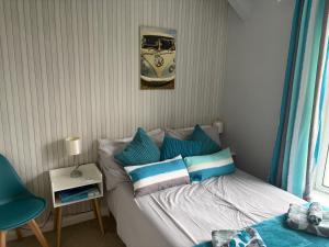 a bedroom with a bed with blue and white pillows at Roseus and Mimosa Cottages in Combe Martin