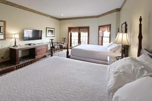 a bedroom with two beds and a desk and a television at Carlisle Inn in Sugarcreek