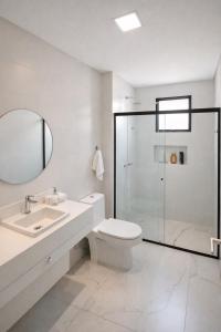 a white bathroom with a toilet and a shower at Summerview novo , 2 piscinas e 2 jacuzzis, 2 quartos Novo! in Itapema