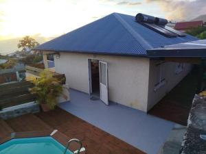 a house with a blue roof with a swimming pool at Location Saisonnière Les Caféiers in Le Tampon