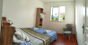 a small bedroom with a bed and a chair at Location Saisonnière Les Caféiers in Le Tampon